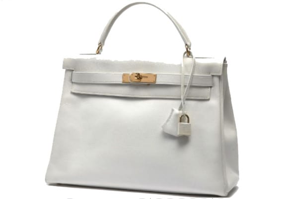 HERMES Paris made in france Sac "Kelly" 32 cm en veau grainé souple blanc, garniture en métal plaqué or, tirette, clochette, clefs, cadenas gainé, doublure en veau grainé blanc comprenant une poche à fermeture sur glissière, une double poche à soufflet, poignée. Année: 1995. Bon état général (quelques légères salissures, marque importante de stylo bleu à l'intérieur environ 8.5 cm). A White springy embossed calfskin leather 32 cm "Kelly" bag, gilt metal hardware, key fob and sheathed padlock, white embossed calfskin leather lining including a slide channel closure pocket, a double gusset pocket, handle. Year: 1995. In good overall condition (tiny spots, and a pencil mark inside). Estimation 3 000 - 5 000 €