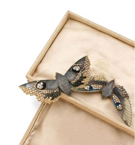 René LALIQUE (1860-1945) Importante broche (c.1907), pouvant être montée en pendentif réalisée en or et figurant deux papillons de nuit en vol à corps en verre blanc satiné et ciselé à la meule, montés sur griffes. Ailes de papillons ornementées d'émaux gris vert et bleu à découpes évidées serties d'émaux translucides dits " plique à jour " et soulignées de diamants de taille ancienne. Le revers est ciselé reprenant au naturel les corps et les ailes des papillons. Epingle et petits anneaux de suspension en or (sans chaîne) Présenté dans son écrin d'origine siglé Place Vendôme. Signée du cachet Lalique frappé en creux sur la tranche de chacun des deux papillons. Largeur : 16.5 cm - Hauteur : 10 cm Estimation 200 000 - 250 000 € Sold for 430,800 €