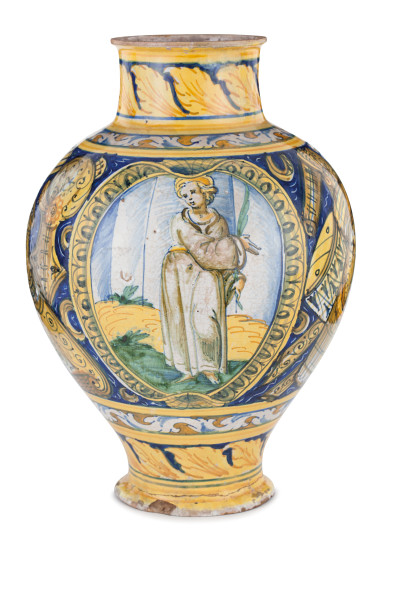 1317. VASO IN MAIOLICA POLICROMA, FORNACE DI SCIACCA, 1593 ovoidale e decorato con figura di Santa Martire nel medaglione con cornice baccellata e sul verso fondo "a trofei", con targa con "SPQR" e altra datata "1593"; qualcheusura e danno minore, il piede con restauro Etichetta cartacea Galleria Bealu, Parigi Alt. cm 35, larg. cm 25 Stima € 3.000 - 4.000 Aggiudicazione € 9.920 