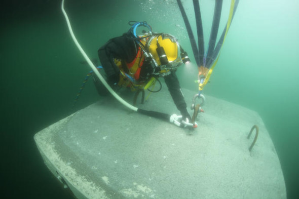 A diver connects a rope made of ultra-high-molecular-weight polyethylene (UHMWPE), covered with a polyester protective layer with a breaking load of 20 metric tons, to one of the anchors on the lakebed to keep the piers in place, March 2016 Photo: Wolfgang Volz