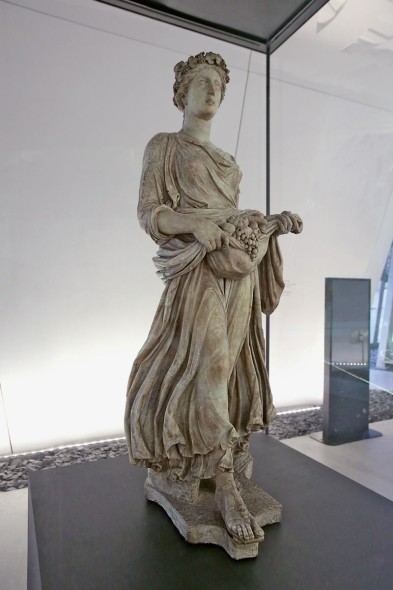 Carpo, I sec. d.C. marmo di Carrara, grandezza naturale Raffigura una delle Horai, divinità legate alla fecondità della terra, figlie di Zeus e di Themis le quali, secondo la mitologia greca, vigilavano sulle stagioni dell'anno proteggendo e favorendo primizie e abbondanti raccolti.   Opera prestata dalla Galleria degli Uffizi, Firenze, esposta nella Corte di Palazzo Italia Crediti fotografici: Photoviews Mourad Balti Touati 