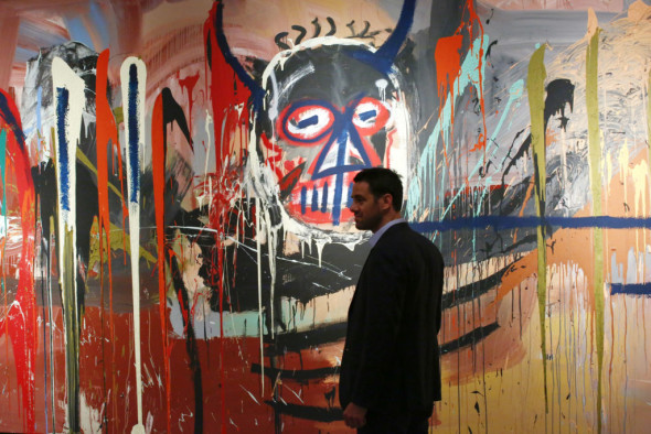 Loic Gouzer Deputy Chairman, Post-War and Contemporary at Christie's stands next to the artwork 'Untitled' made by artist Jean-Michel Basquiat on April 29, 2016 during a press preview of Christie's forthcoming evening auctions of the Contemporary, Impressionist, Modern and Post-War Art in New York. As part of the 20th Century season in New York, the Post-War and Contemporary Art Evening Sale takes place on 12 May, featuring some of the leading modern masters and contemporary stars of today. / AFP / KENA BETANCUR / RESTRICTED TO EDITORIAL USE - MANDATORY MENTION OF THE ARTIST UPON PUBLICATION - TO ILLUSTRATE THE EVENT AS SPECIFIED IN THE CAPTION        (Photo credit should read KENA BETANCUR/AFP/Getty Images)