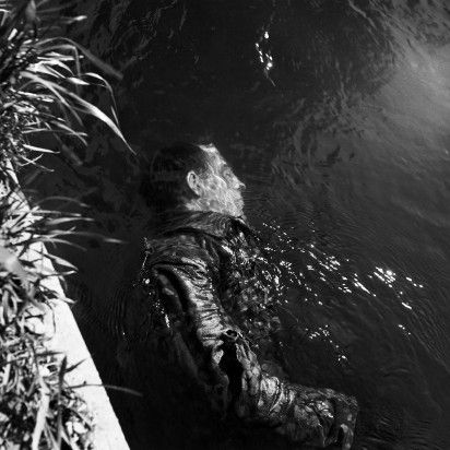 SS GUARD IN CANAL, DACHAU, GERMANY, 1945 by LEE MILLER