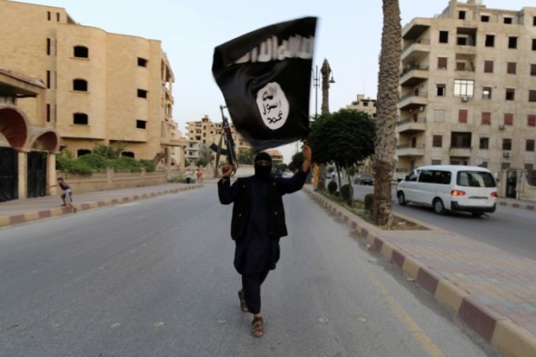 Un miliziano sventola la bandiera dell'Isis a Raqqa, roccaforte dello Stato Islamico in Siria. Credit: Reuters
