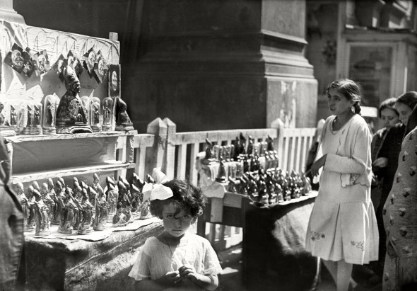 Festa di San Gennaro, bambina davanti a una bancarella con statuette del santo (Studio Troncone, anni Trenta)