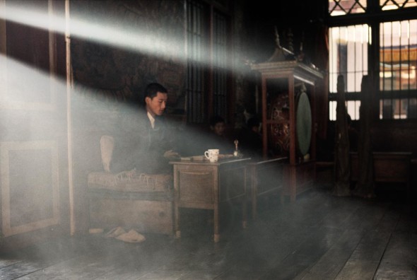 - La luce che filtra dalle finestre incornicia un Rinpoche (lama reincarnato) mentre tiene la Puja (preghiera) mattutina. Sakya Choling Gompa, Darjeeling, India, 2006.