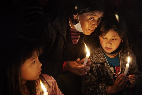 - Una donna Tibetana, con i suoi figli, partecipa ad una veglia per ricordare i tibetani che si sono dati fuoco in segno di protesta contro il governo cinese. Bodh Gaya, Bihar, India, 2012.